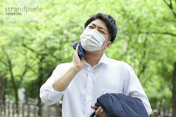 Japanischer Geschäftsmann wischt sich den Schweiß mit einem Taschentuch ab