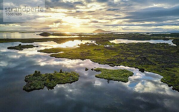 Luftaufnahme von kleinen grünen Inseln im See  Sonne bricht durch dramatische Wolken  die sich im See spiegeln  Myvattn  Skútustaðir  Norðurland eystra  Island  Europa