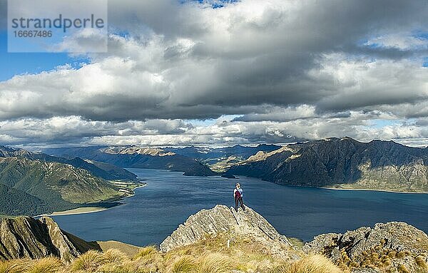 Wanderin steht auf einem Felsen  Ausblick über Lake Hawea  See und Berglandschaft im Abendlicht  Ausblick vom Isthmus Peak  Wanaka  Otago  Südinsel  Neuseeland  Ozeanien