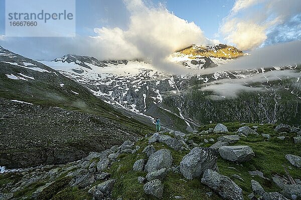 Wanderin blickt auf Berggipfel mit letztem Sonnenlicht  Berglandschaft mit Wolken  Berliner Höhenweg  Zillertaler Alpen  Zillertal  Tirol  Österreich  Europa