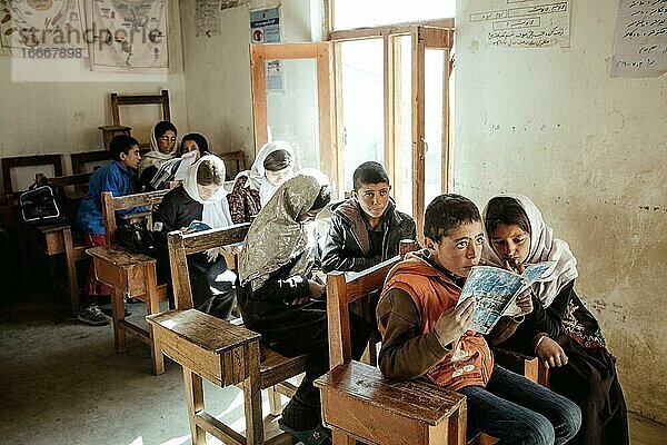 Kinder im Klassenzimmer  ein Mädchen und ein Junge lesen gemeinsam aus einem Heft  Potokh Primary School  Potokh  Wakhan-Korridor  Afghanistan  Asien