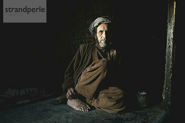 Ladenbesitzer sitzt im Halbdunkel auf dem Boden seines Geschäfts  Ishkashim  Afghanistan  Asien
