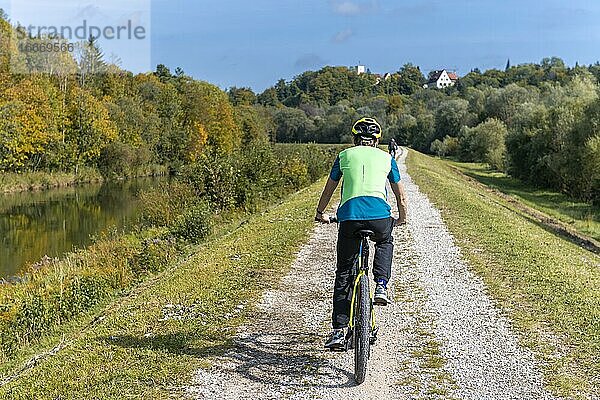 Farhrradfahrer auf Fahrradweg auf dem Kanaldamm der Isar  hinten Grünwalder Burg  Grünwald  Oberbayern  Bayern  Deutschland  Europa