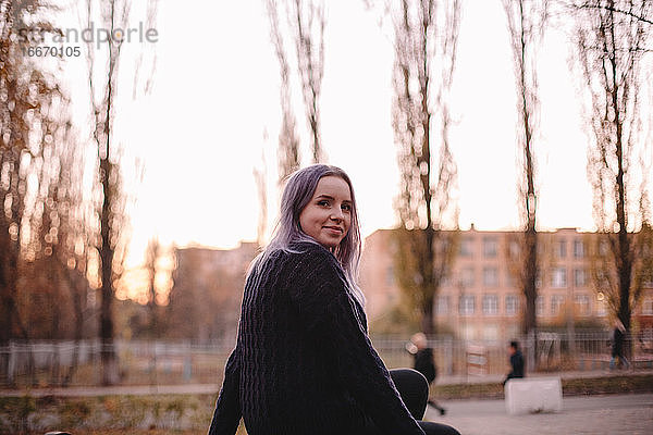 Glückliche Hipster junge Frau sitzt im Park im Herbst