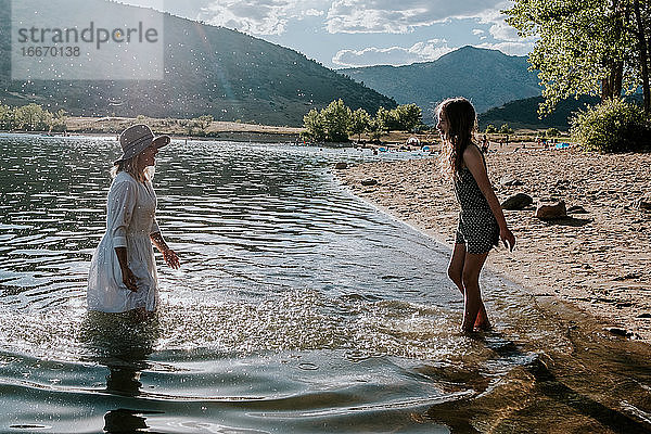 Mutter und Tochter planschen und spielen am Ufer eines Sees