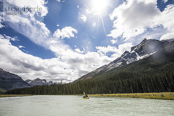 Fernblick auf eine Person  die in den Rocky Mountains mit einem Kajak (Packraft) paddelt.