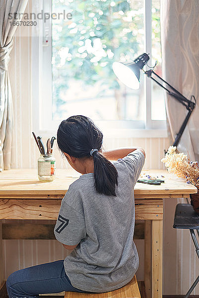 Seltener Blick auf ein Mädchen bei der Arbeit am Holztisch