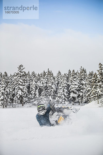 Rückansicht eines erfahrenen Fahrers  der mit dem Motorschlitten durch den Pulverschnee fährt.