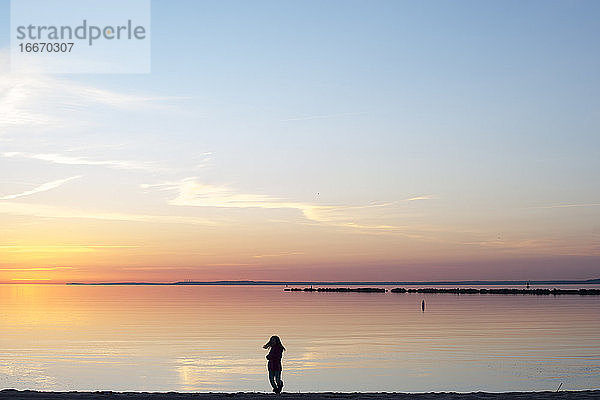 Silhouette eines jungen Mädchens am Strand bei Sonnenaufgang