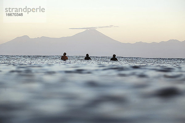 Surfer auf dem Surfbrett auf dem Meer  die auf eine Welle warten  Vulkan Rinjani