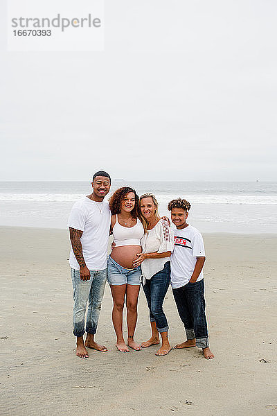 Familie posiert für Mutterschaftsfotos am Strand