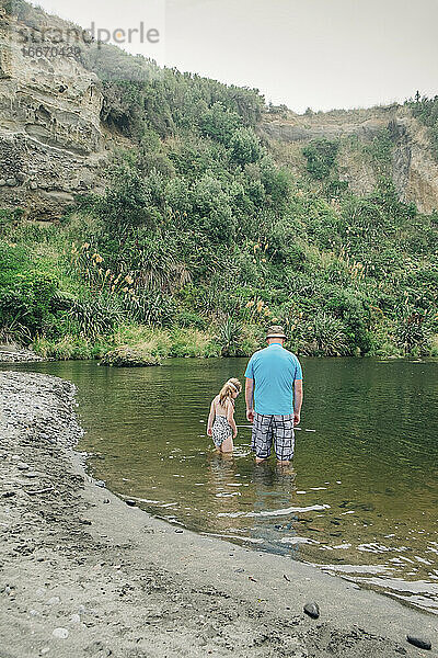 Vater und Tochter spielen im Wasser an einem malerischen Flussabschnitt