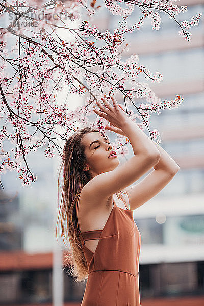 Modeporträt einer jungen Frau im Jumpsuit unter dem Blütenbaum