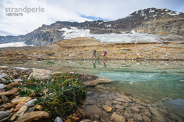 Rucksacktouristen beim Wandern entlang eines Bergsees in der Nähe eines Gletschers in Yoho
