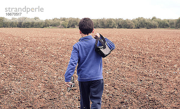 Junge läuft durch das Feld und nimmt seine Drohne mit  um sie zu blasen
