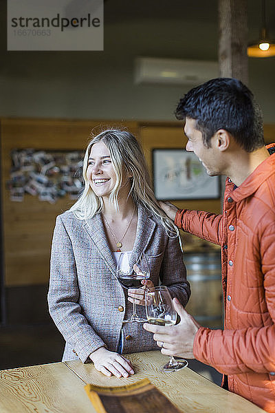 Ein junges Paar genießt Wein auf einer Terrasse eines Weinguts in Oregon.