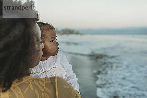 Seitenansicht von Mutter und Tochter  die sich im Ozean umarmen