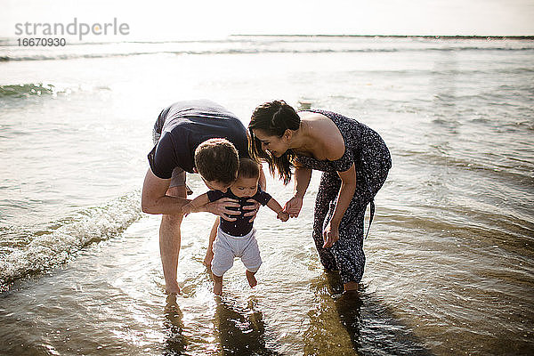 Eltern Mitte 30  die mit ihrem kleinen Sohn im Meer spielen