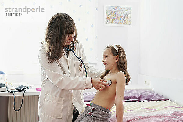 Seitenansicht eines Kinderarztes  der ein kleines  fröhliches Mädchen mit
