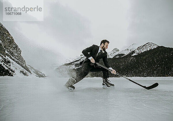 Eishockeyspieler auf zugefrorenem See im Anzug hält schnell an und spritzt Eis