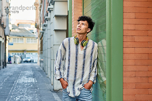 Junger afro-haariger Mann mit Kopfhörern schaut auf