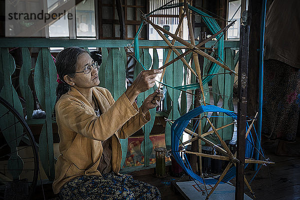 Ältere birmanische Frau beim Aufwickeln von Fäden in einer Textilwerkstatt  Inle-See  Myanmar