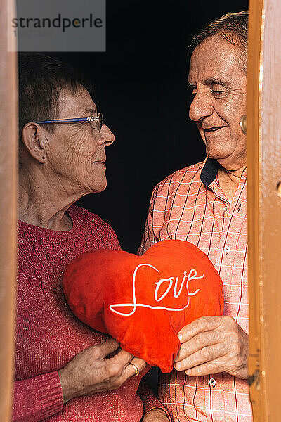 Glückliches liebendes älteres Paar mit rotem Herzgeschenk