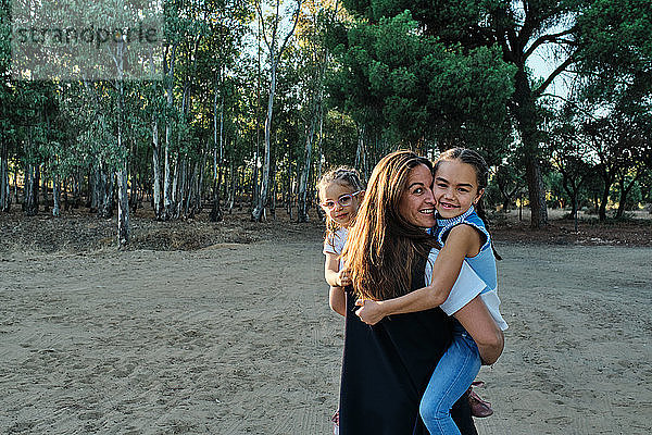 eine glückliche Mutter nimmt ihre beiden Töchter und lächelt
