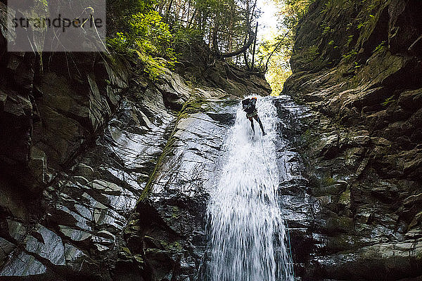 Abseilen eines Forschers in einem Wasserfall aus geringer Höhe