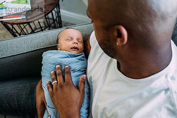 Neugeborenes Baby in den Armen des Vaters schlafend