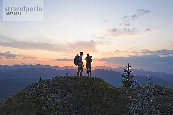 Paar Reisende Mann und Frau sitzen auf einer Klippe und beobachten den Sonnenuntergang