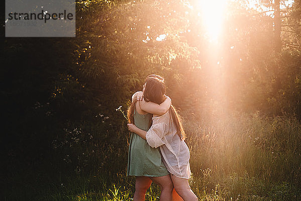 Lesbisches Paar umarmt sich im Sommer im Wald