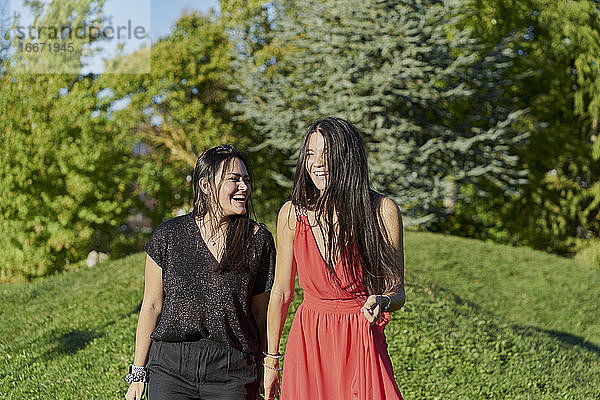 Junge Frauen Paar hält die Hände zu Fuß auf grünem Gras in einem Park an einem sonnigen Tag. romantisches Konzept