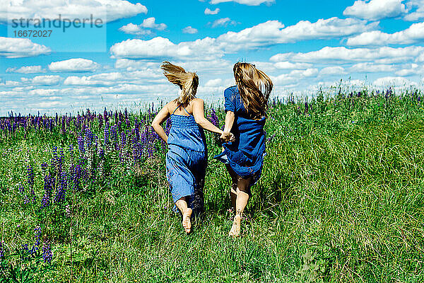 Zwei Mädchen laufen auf der Sommerwiese