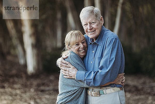 Porträt eines erwachsenen Paares im Ruhestand  das sich im Wald umarmt