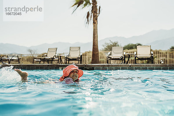 Seitenansicht des kleinen Mädchens in rosa Hut Schwimmen im Pool