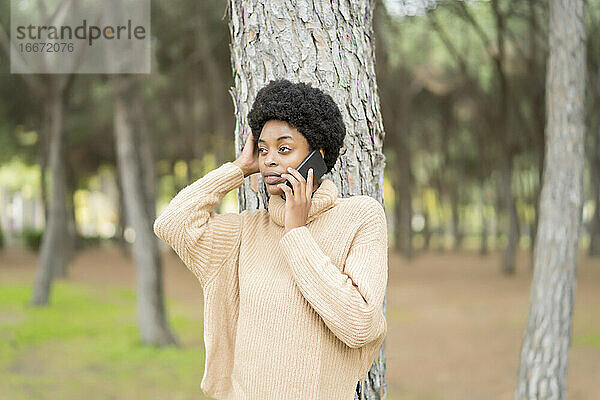 Afrikanische Frau  die im Park auf ihr Smartphone spricht