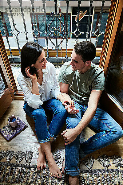 Draufsicht auf ein junges  intimes Paar  das sich zu Hause am Fenster auf dem Balkon entspannt.