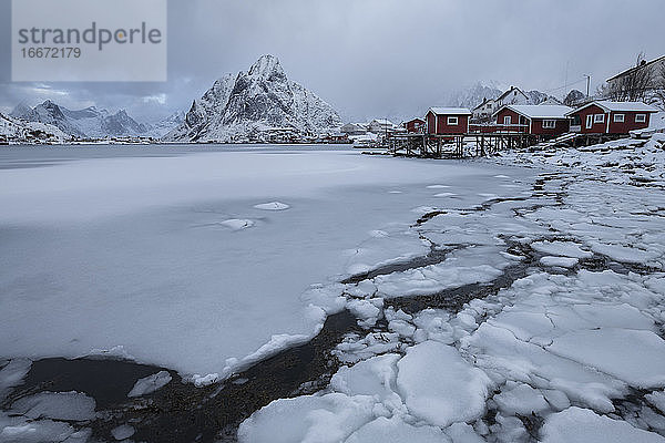 Der Gipfel des Olstind erhebt sich über der zugefrorenen Bucht von Reine  Moskenesøy  Lofoten  Norwegen