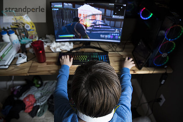 High View of Teen Boy Spielen auf Gaming-Computer auf unordentlichen Schreibtisch