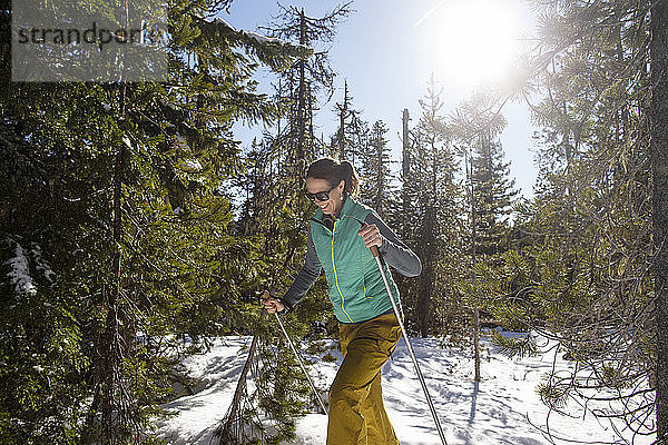 Eine junge Frau fährt an einem sonnigen Tag in der Nähe von Mt. Hood Langlaufski.