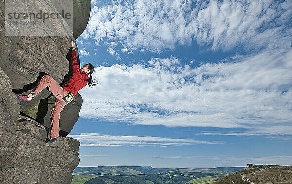 Frau beim Bouldern an den Windgather-Felsen im britischen Peak District