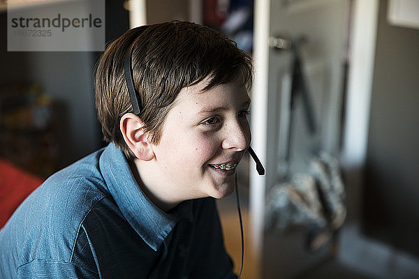 Seitenansicht eines lächelnden Teenagers mit Zahnspange  der ein Gaming-Headset trägt