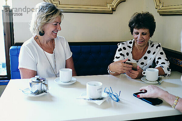 Lächelnde Frauen beim Kaffeetrinken mit ihren Freunden