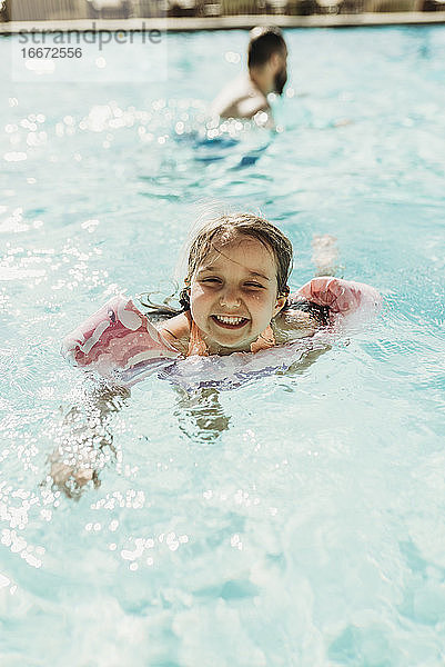 Lifestyle-Porträt eines jungen Mädchens beim Schwimmen im Hotelpool im Urlaub