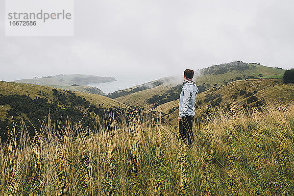 Frau im blauen Hemd betrachtet die Landschaft  Banks Peninsula  NZ