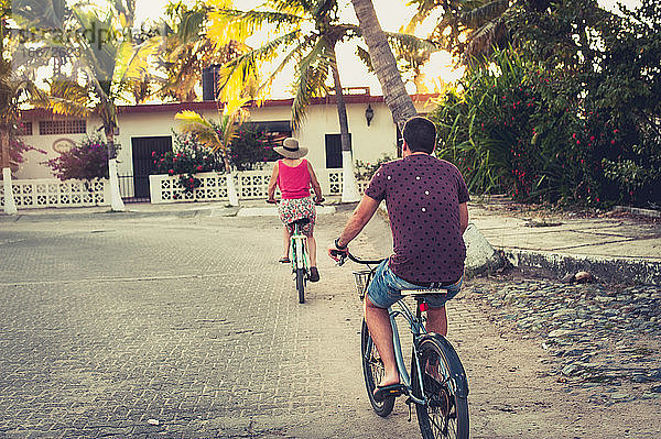 Mann und Frau fahren Fahrrad in einer tropischen ländlichen Stadt