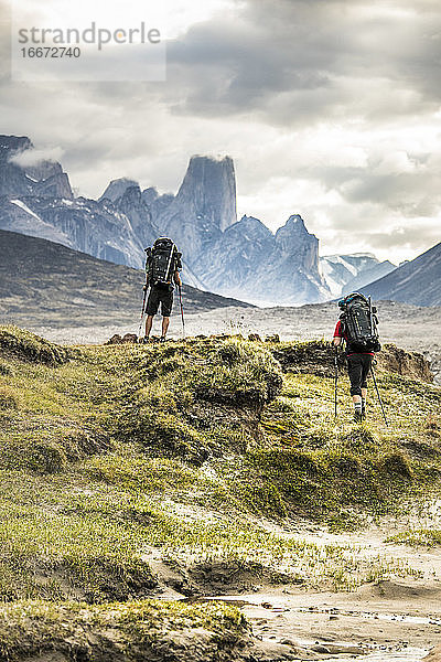 Zwei Bergsteiger wandern über einen dramatischen Bergpass.