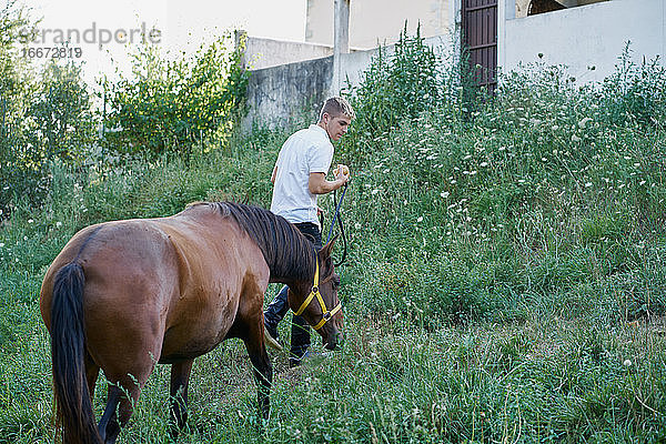 Porträt eines blonden jungen Mannes mit einem Pferd