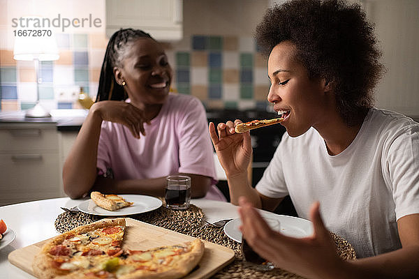 Schwarze Frau isst Pizza in der Nähe eines Freundes